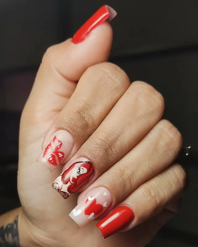 Set de uñas rojas para San Valentín con corazones, labios pintados a mano y detalles en glitter.