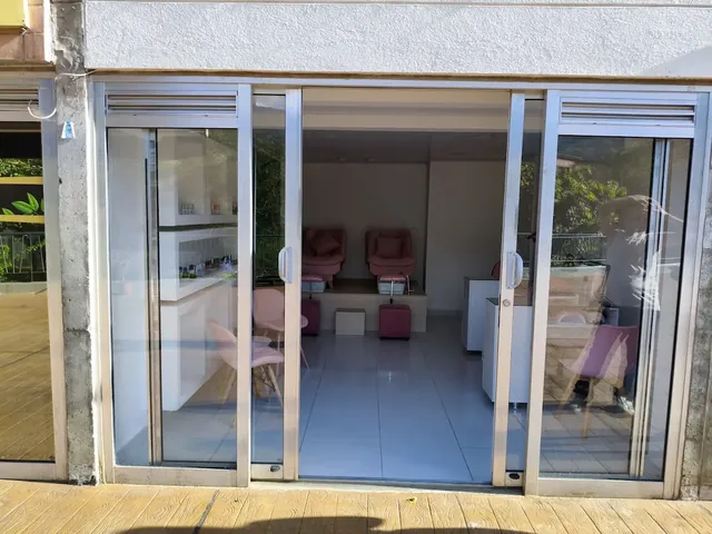 Fachada del local 109 con puertas corredizas de vidrio, desde donde se ven los sillones rosados del estudio.